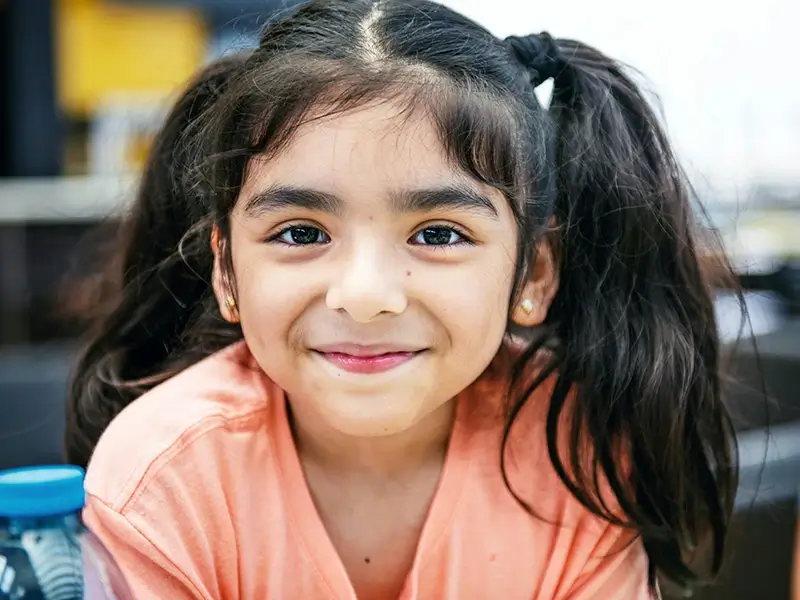 A young girl with pigtails smiles softly